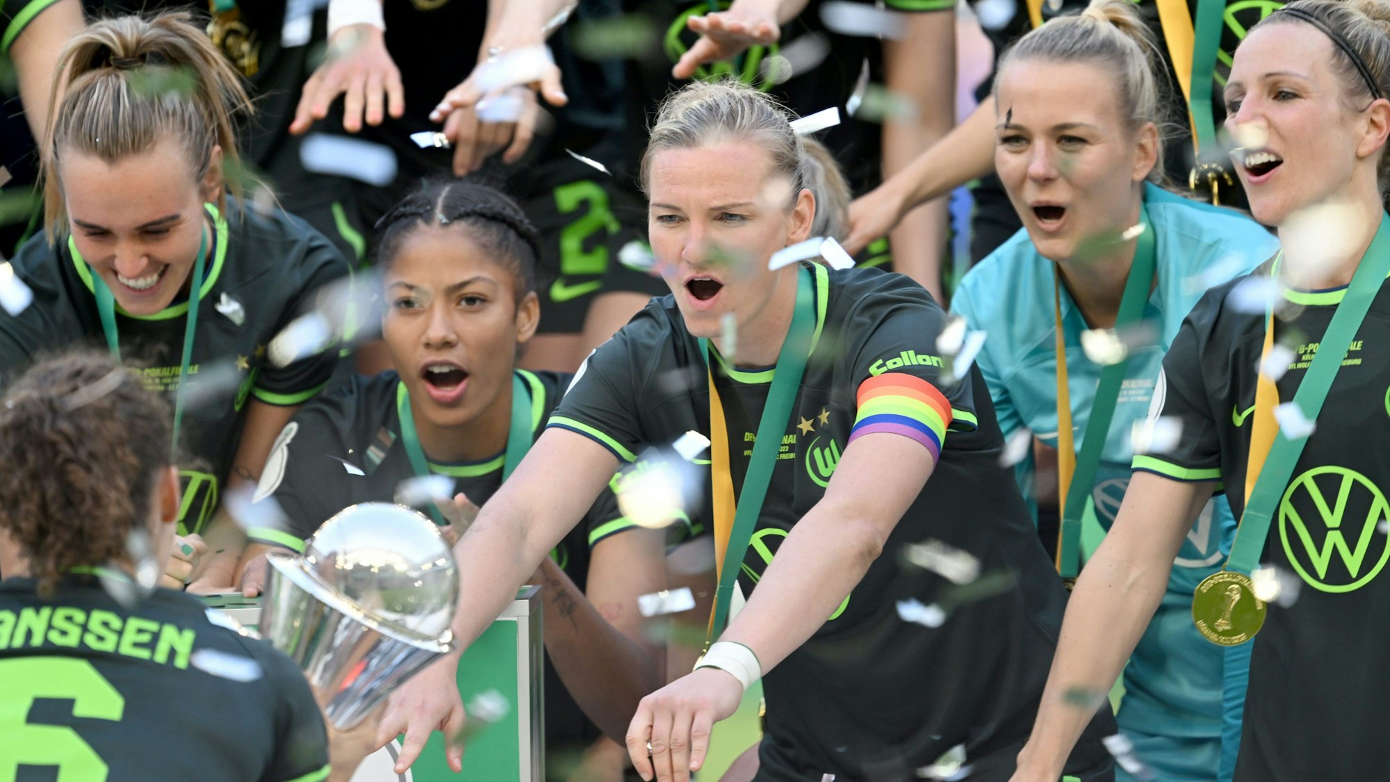 Die Wolfsburgerin Dominique Janssen (unten, l) streckt den Spielerinnen, darunter Kapitänin Alexandra Popp (M), bei der Siegerehrung den Pokal entgegen.