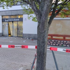 Das Bild zeigt einen von der Polizei abgesperrten Bereich, in dem die zerstörte Tür der Mechernicher Volksbank-Filiale zu sehen ist.