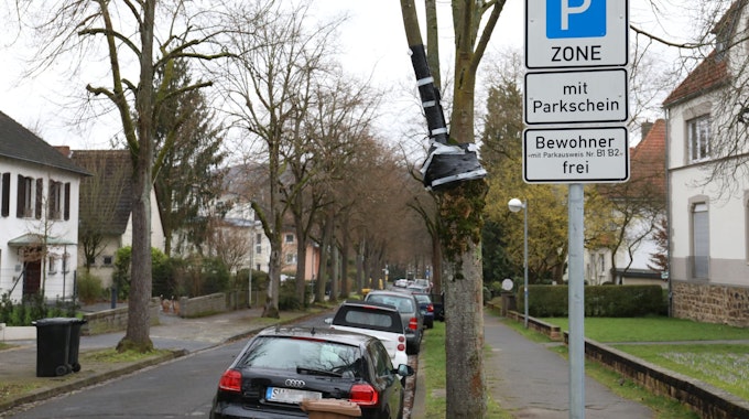 Ein Straßenschild weist die Giradetallee in der Bad Honnefer City als parkgebührenpflichtig aus. Am rechten Fahrbahnrand parken Autos.