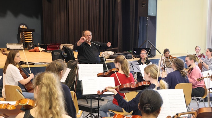 Ein Dirigent leitet ein junges Orchester an.