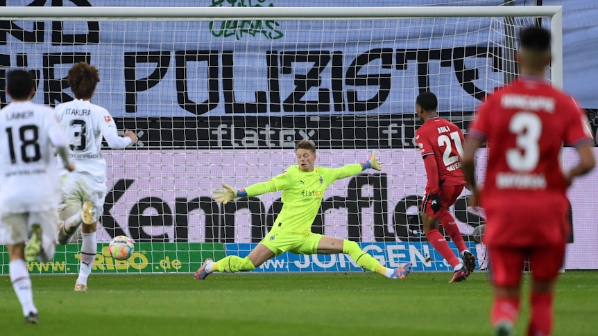 Amine Adli (Nummer 21) erzielt im Bundesliga-Spiel von Bayer Leverkusen bei Borussia Mönchengladbach am 22. Januar 2023 den Treffer zum zwischenzeitlichen 2:0. Jonas Omlin versucht vergeblich, den Ball zu parieren.