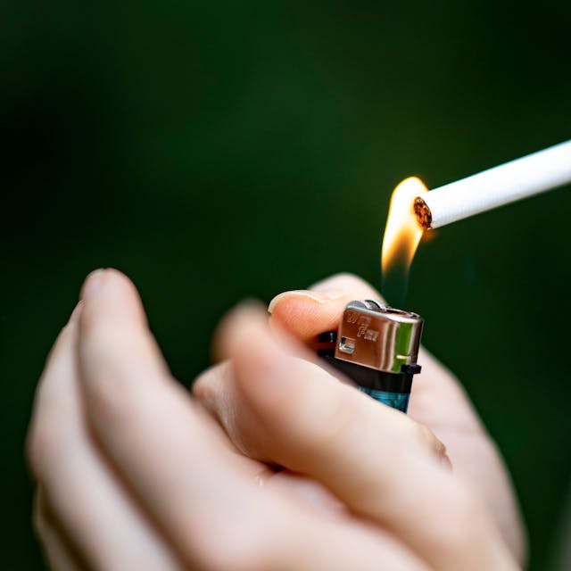 Eine Frau zündet sich mit einem Feuerzeug eine Zigarette an.