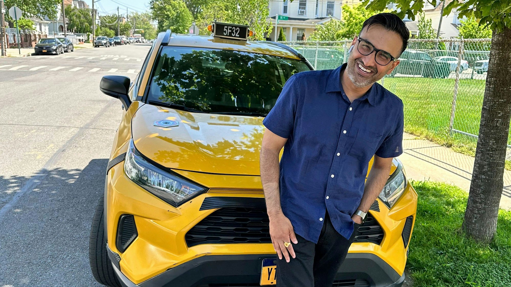 Sukhcharn Singh, Taxifahrer aus New York, steht lächelnd vor seinem Taxi im New Yorker Stadtbezirk Queens.