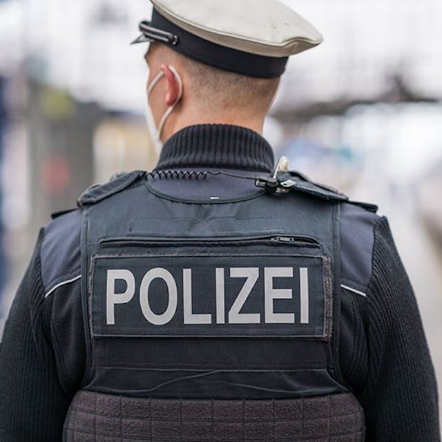 Auf der Weste eines Polizisten steht der Polizei-Schriftzug (Symbolbild)