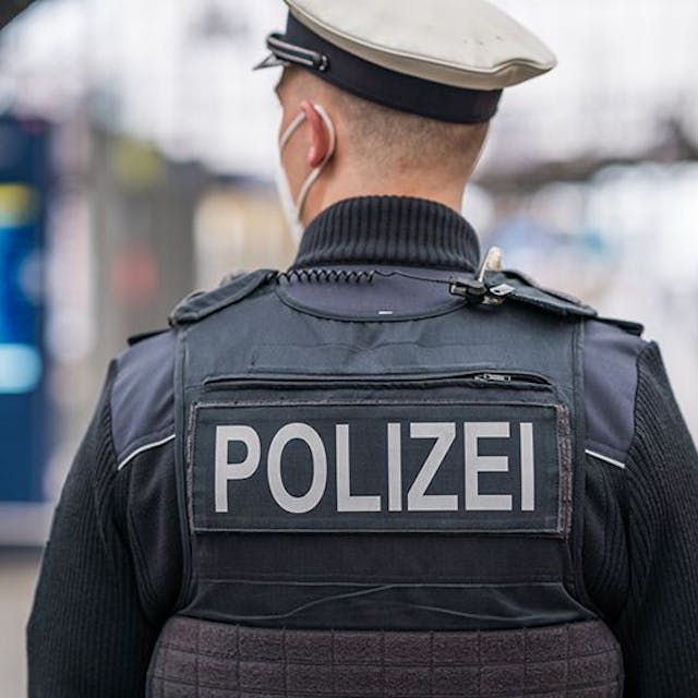 Auf der Weste eines Polizisten steht der Polizei-Schriftzug (Symbolbild)