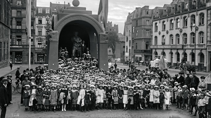 Hunderte Schülerinnen stehen 1915 vor der Figur des Kölschen Boor.