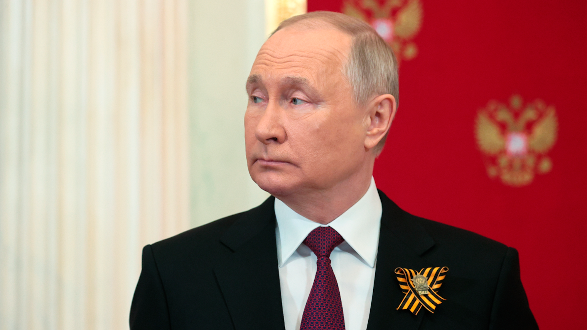 Wladimir Putin in einem schwarzen Anzug mit dunkelroter Krawatte.