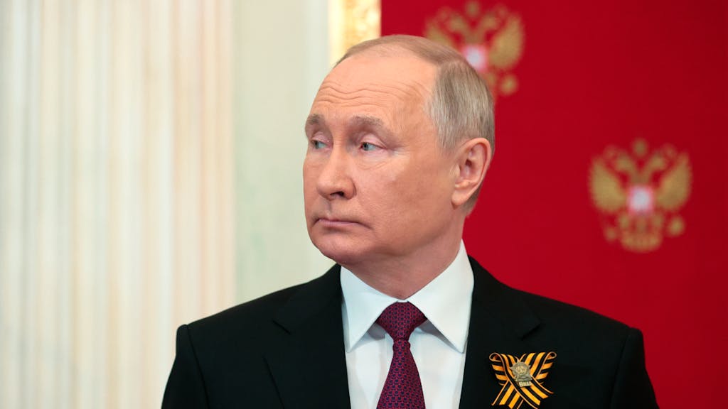 Wladimir Putin in einem schwarzen Anzug mit dunkelroter Krawatte.