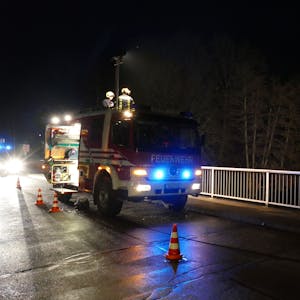 Ein Feuerwehrauto steht an einer mit Hütchen abgesperrten Brücke im Dunkeln auf der Straße. (Symbolbild)