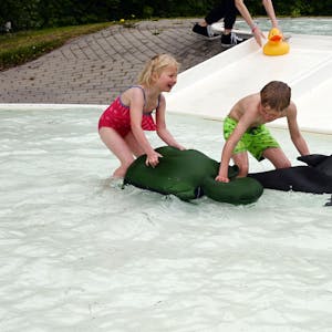 Im Bild sind ein Junge und seine kleine Schwester, die in einem Schwimmbecken für Kinder mit zwei aufblasbaren Tieren spielen.&nbsp;