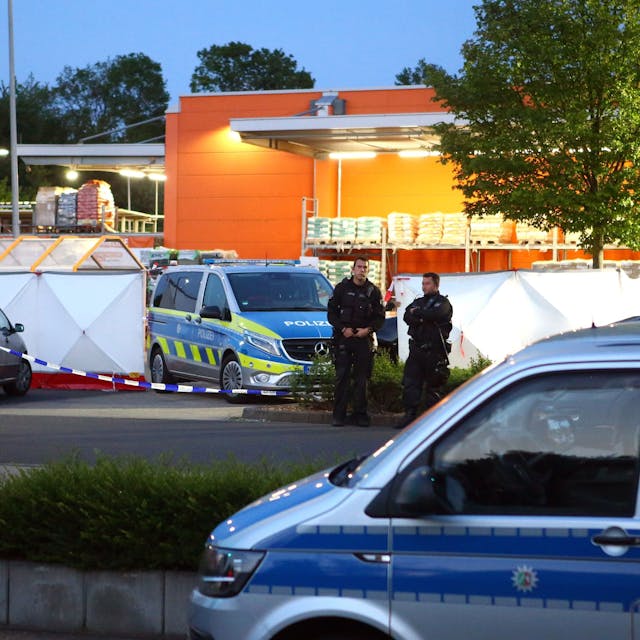Polizisten stehen am Tatort auf dem Parkplatz eines Aachener Baumarkts.