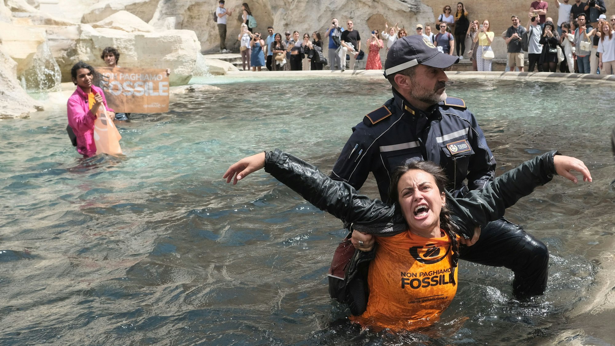 Klimaaktivisten und -aktivistinnen der „Letzten Generation“ werden von Polizisten aus dem Wasser des Trevi-Brunnen in Rom geleitet.