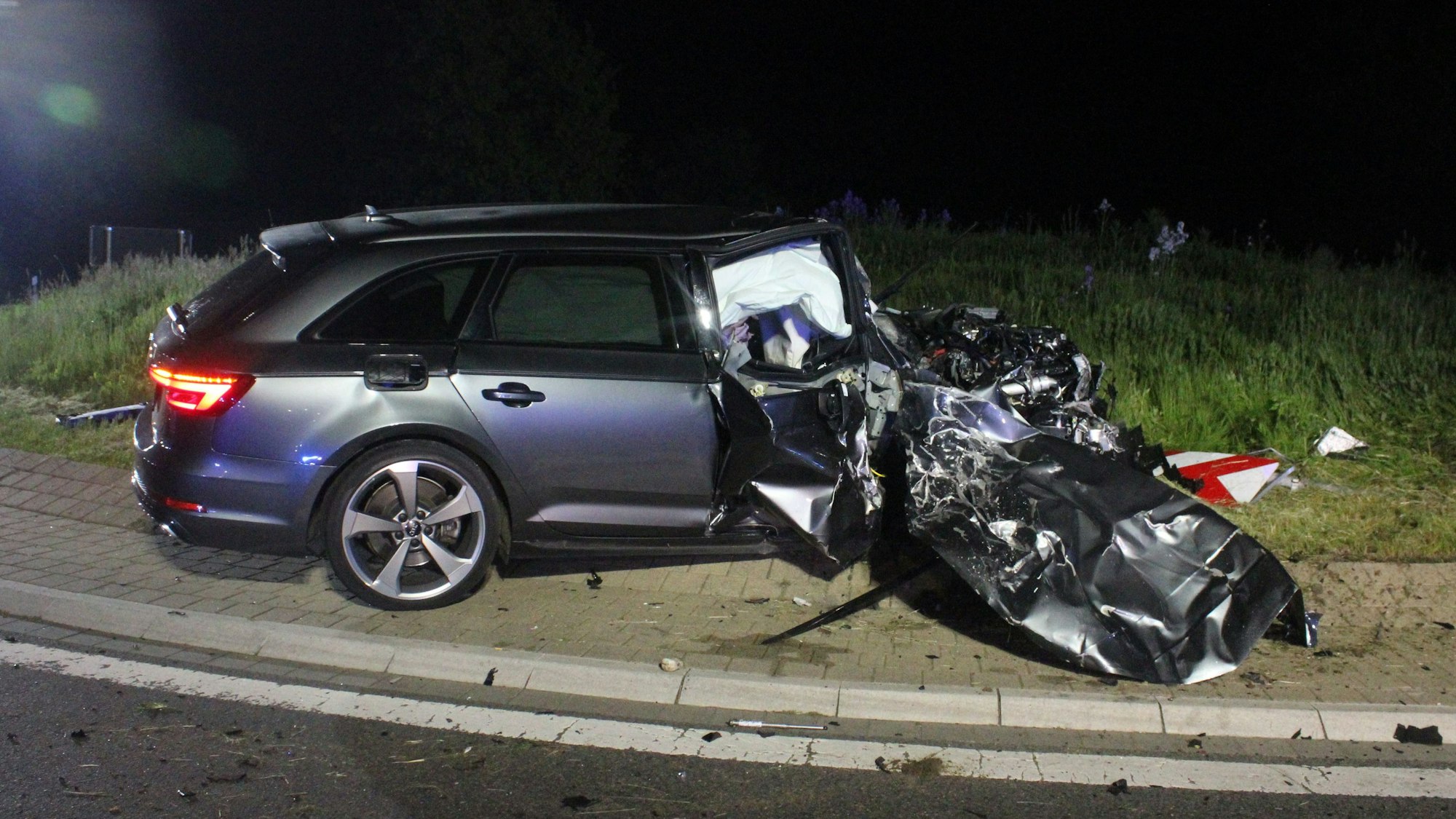 Ein Pkw-Kombi steht auf einem Kreisverkehr, seine Motorhaube sowie der Fahrerraum sind völlig zerstört.
