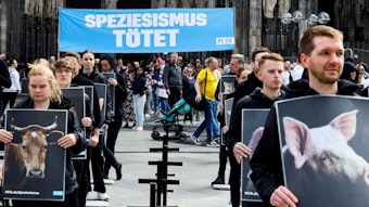 In schwarz gekleidete Demonstranten halten Schilder mit Tieren in der Hand.