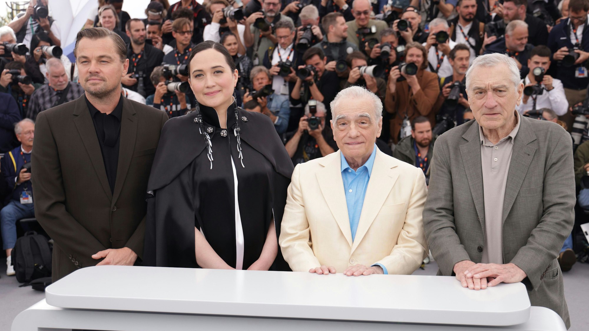 Die Schauspieler stehen nebeneinander in Cannes für einen Fototermin. Sie sind schick angezogen.