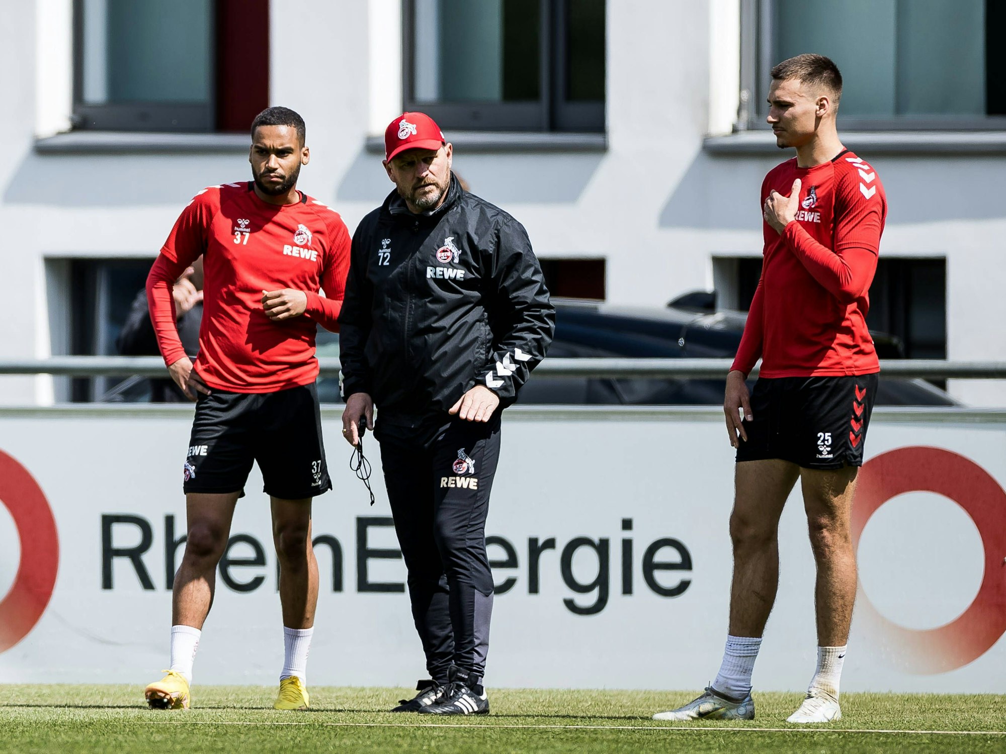 Steffen Baumgart steht beim Training des 1. FC Köln mit Tim Lemperle und Linton Maina auf dem Platz.