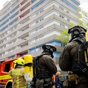 11. Mai: Polizeibeamte mit Gasmasken und Feuerwehrleute stehen vor dem Hochhaus in Ratingen, wo ein 57-Jähriger bewusst eine Explosion herbeigeführt haben soll.