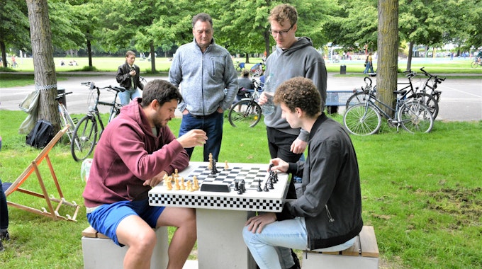 Zwei Männer sitzen im Inneren Grüngürtel vor einem Schachbrett.