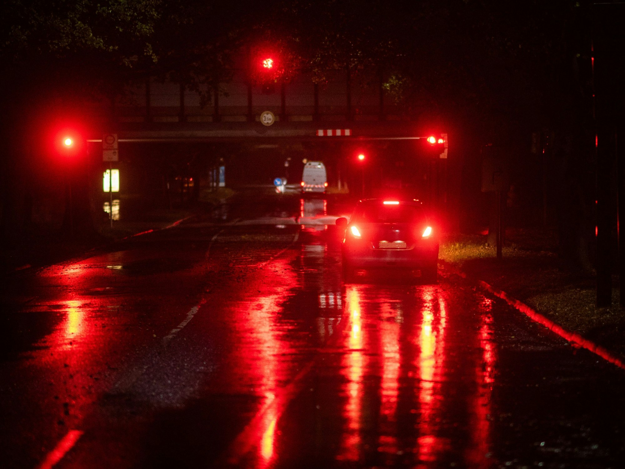 Ein Auto steht am frühen Morgen bei regnerischem Wetter an einer roten Ampel.