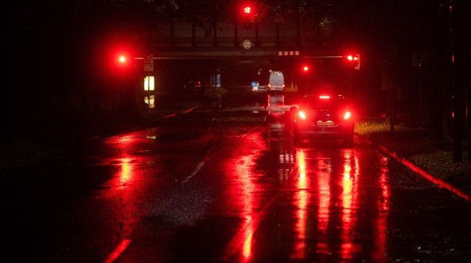 Ein Auto steht am frühen Morgen bei regnerischem Wetter an einer roten Ampel.&nbsp;
