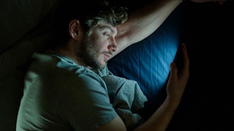 Ein Mann liest im Bett auf dem Smartphone
