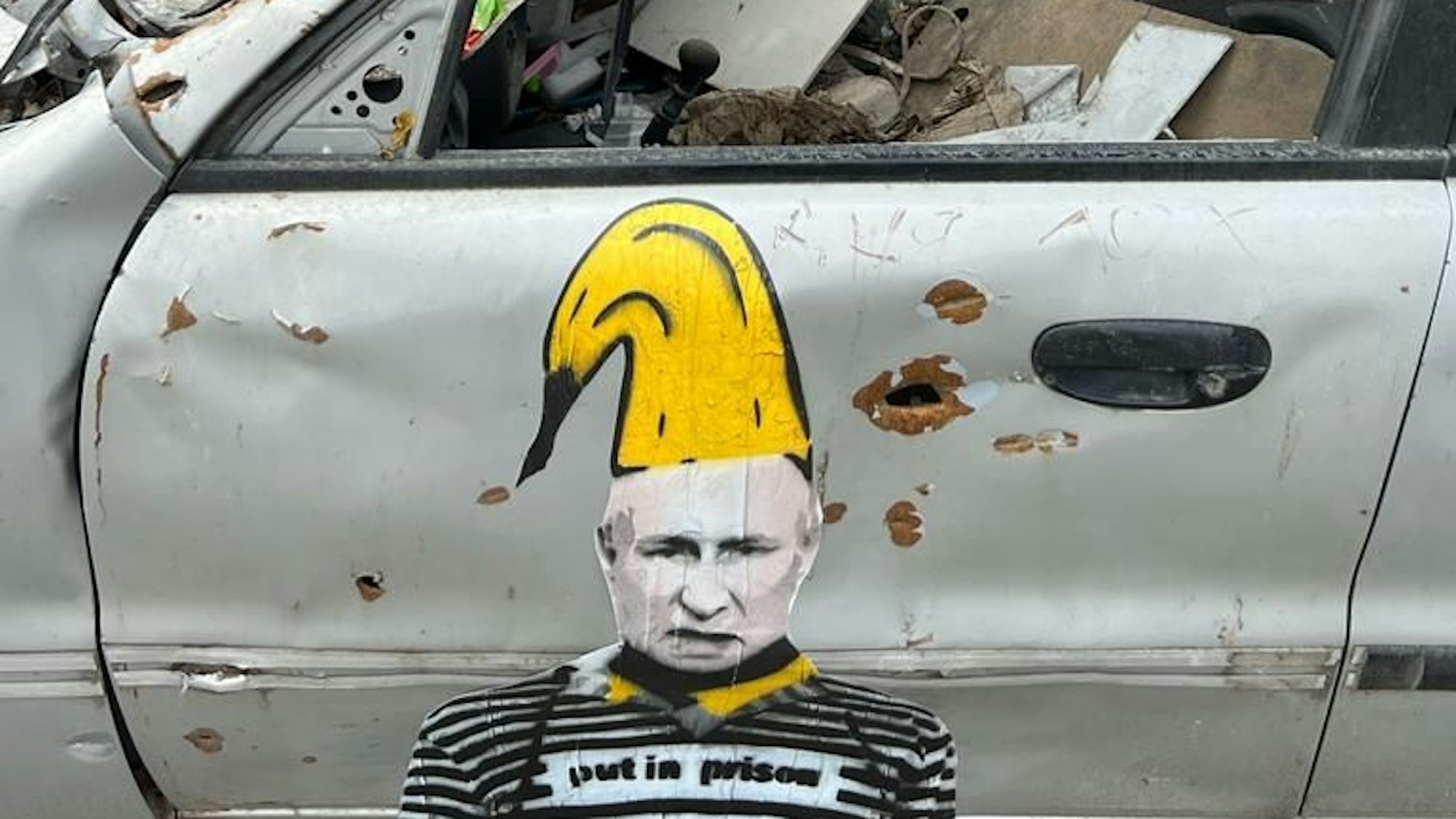 Ein Putin-Motiv von Thomas Baumgärtel auf einem zerstörten Fahrzeug in der Ukraine.
