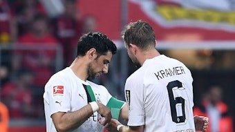 Christoph Kramer (r.) überreicht an Lars Stindl (l.) die Kapitänsbinde von Borussia Mönchengladbach. Das Foto zeigt die beiden am 21. Mai 2023 während des Bundesliga-Duells bei Bayer Leverkusen. Kramer macht die Binde an Stindls Arm fest.