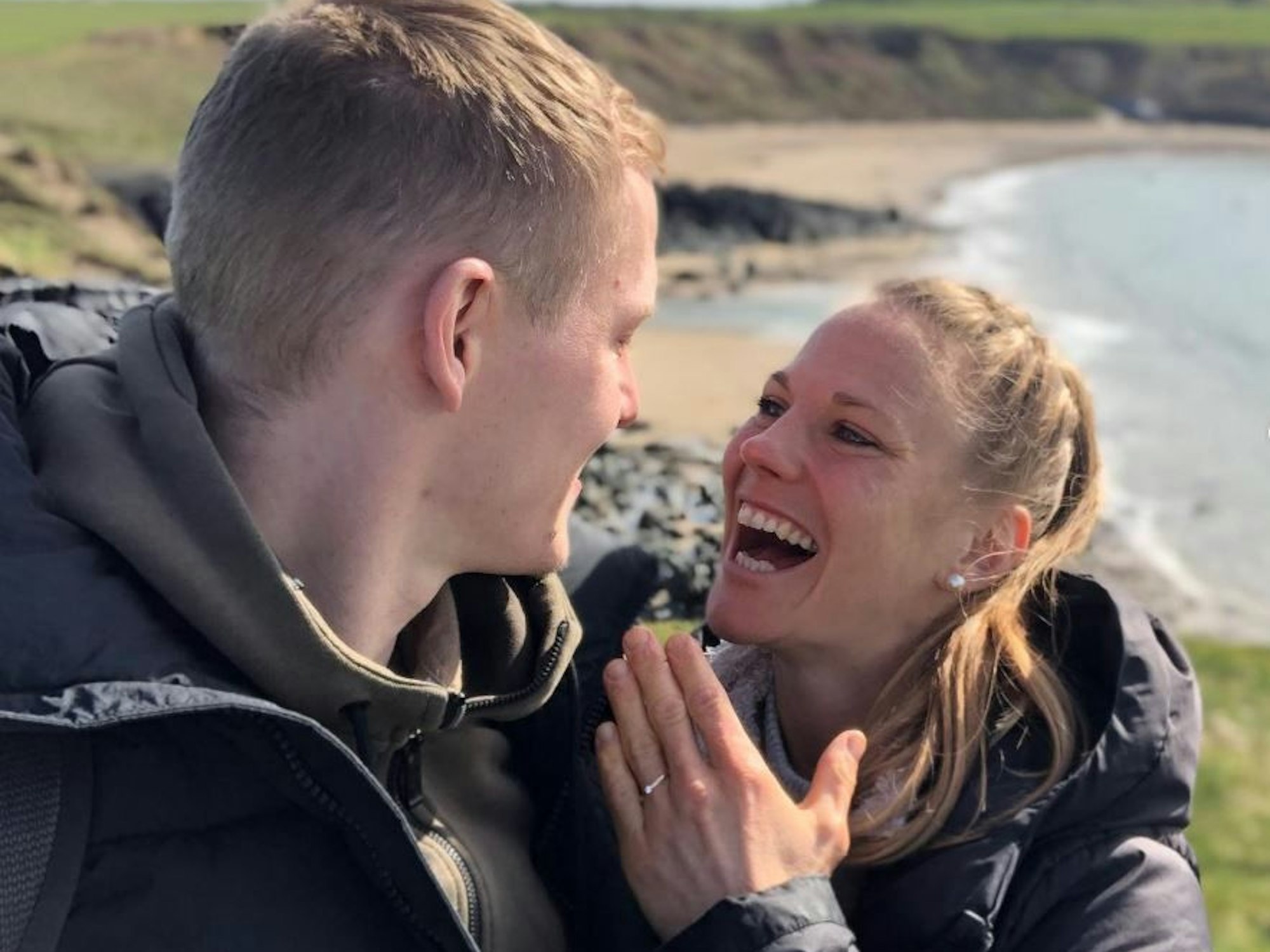 Leonie Maier und ihr Freund stehen vor der walisischen Küste, Maier trägt einen Verlobungsring an der linken Hand.