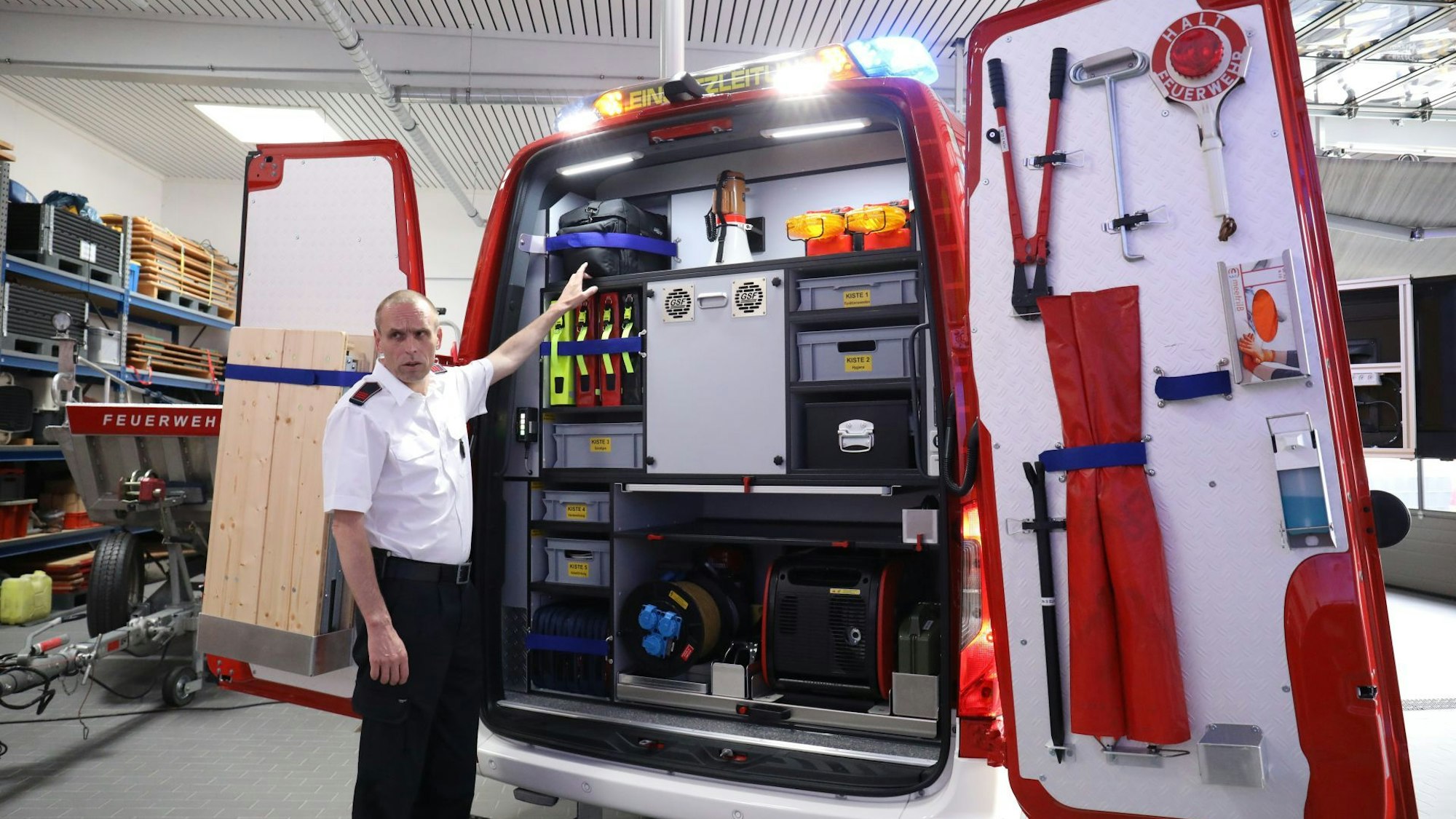 Feuerwehrmann Markus Prinz steht an der geöffneten Hecktür des neuen Einsatzleitwagens und zeigt Ausrüstungsgegenstände der Feuerwehr, darunter ein Notstromaggregat.