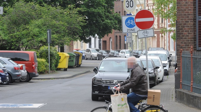 Die Fahrradzone in der Frechener Innenstadt. Ein Mann fährt auf einem Fahrrad über die Straße. Im Hintergrund markiert ein Schild die Fahrradzone.