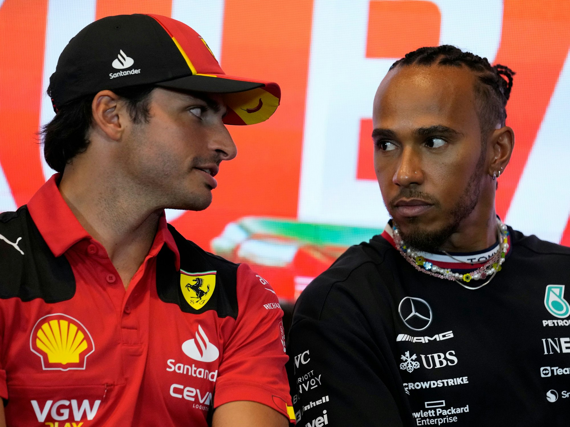 Carlos Sainz (l) aus Spanien vom Team Scuderia Ferrari unterhält sich mit Lewis Hamilton aus Großbritannien vom Team Mercedes-AMG Petronas Motorsport während einer Pressekonferenz.