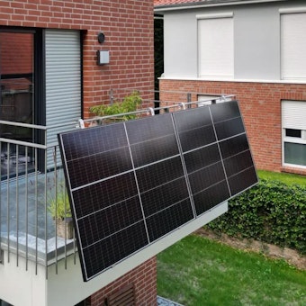 Zwei Solarmodule als Balkonkraftwerk sind an einem Gitterbalkon angebracht.