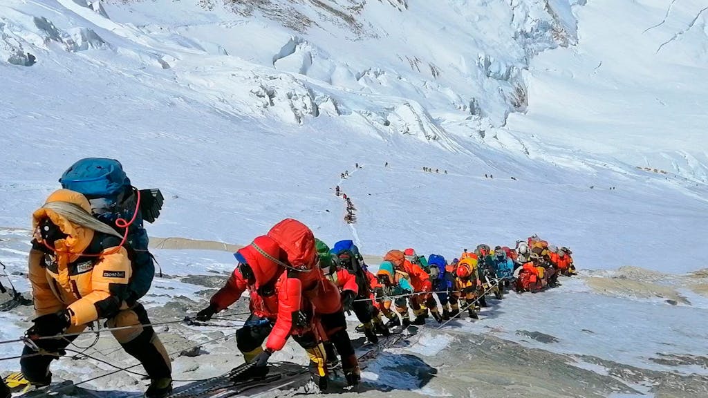 In einer langen Schlange klettern Bergsteigerinnen und Bergsteiger auf dem Mount Everest.