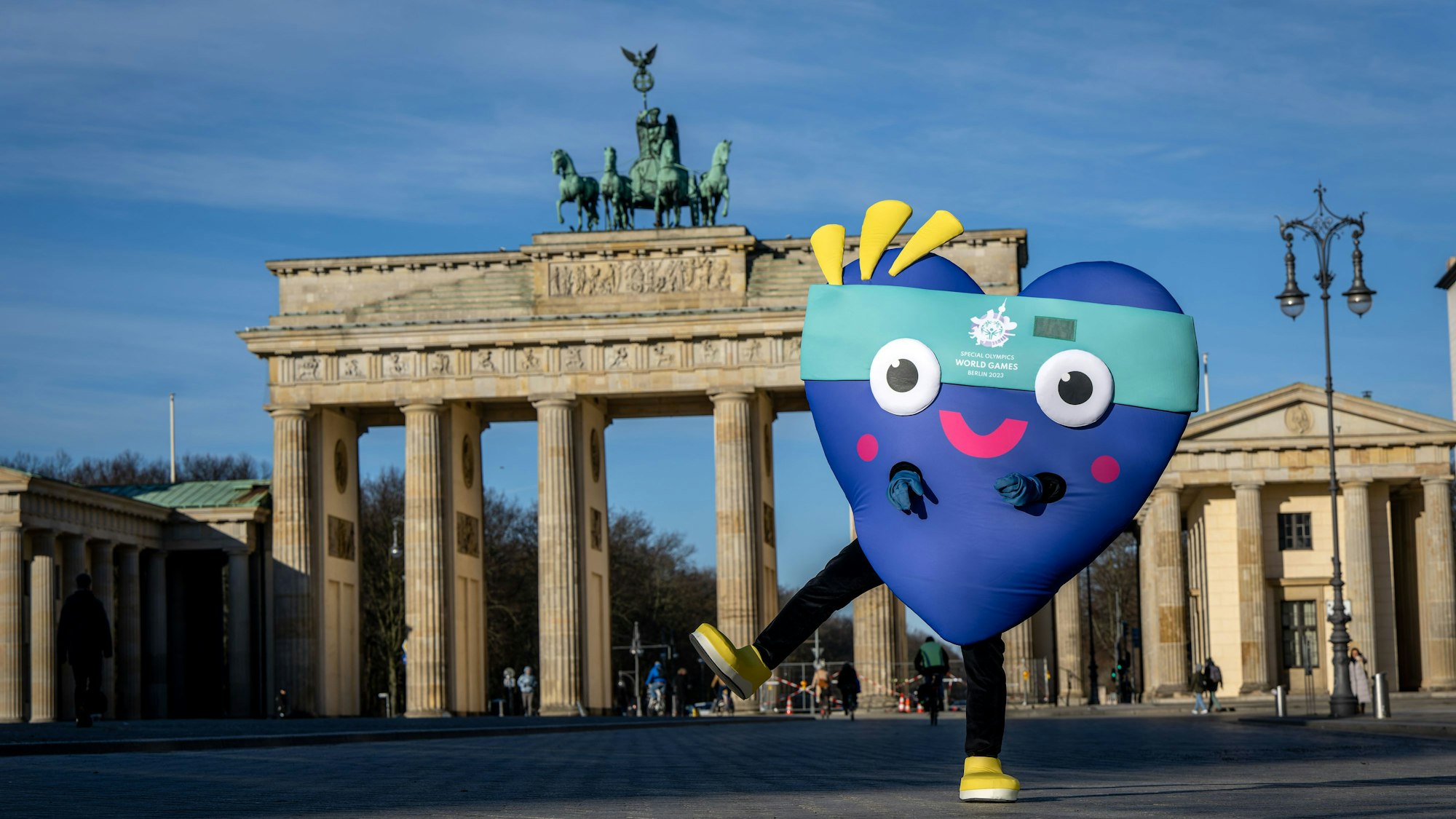 Ein Maskottchen steht vor dem Brandenburger Tor in Berlin.