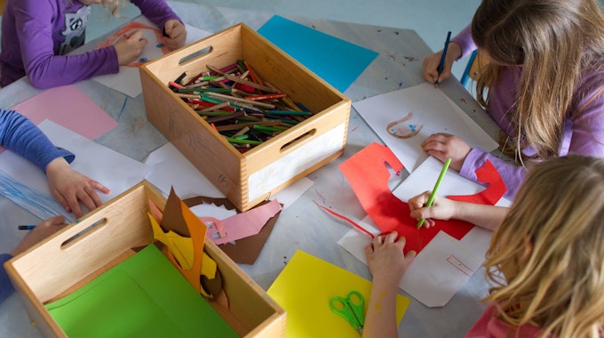 Das Foto zeigt, wie Kinder in einer Kita malen und basteln.