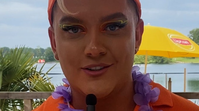 Das Foto ist ein Screenshot aus einem TikTok-Video von EXPRESS.de und zeigt eine Nahaufnahme von Influencer Twenty4Tim. Er trägt eine orangefarbene Käppi und ist um die Augen bunt geschminkt.&nbsp;