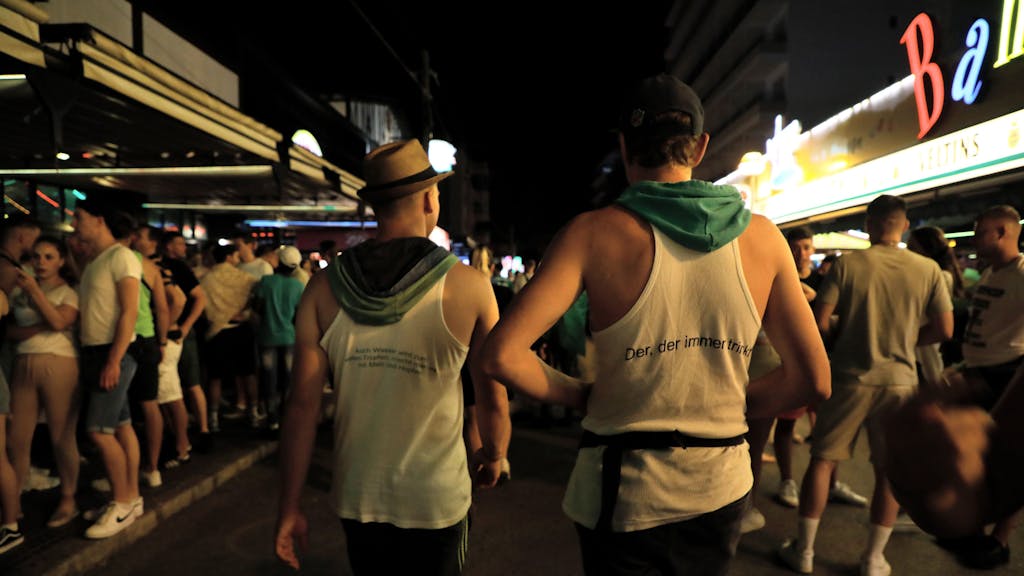 Vorwiegend junge Leute gehen am Abend des 1. Juli 2022 durch die Schinkenstraße im Party-Viertel Ballermann auf Mallorca.