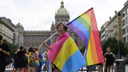 Eine Person trägt eine Regenbogenfahne und eine Pride-Fahne der Pansexuellen auf dem Prager Pride-Festival.&nbsp;