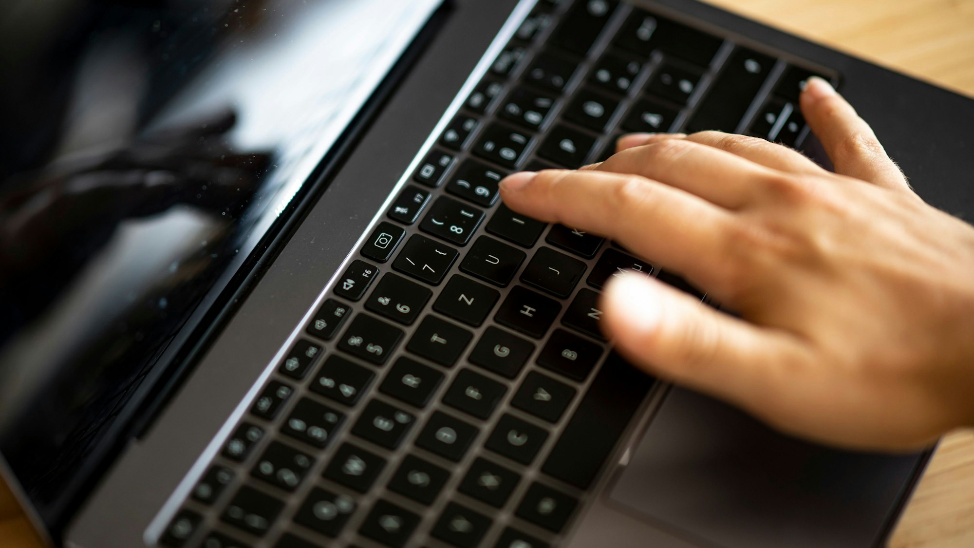 Ein Mann tippt auf der Tastatur eines Laptops.