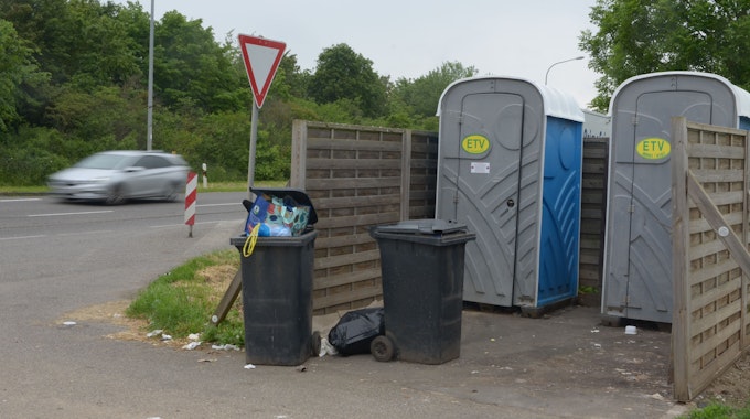 Das Bild zeigt zwei volle Mülltonnen und zwei mobile Toiletten im Euskirchener Industriepark.