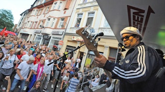 
Ein Gitarrist spielt auf der Hauptstraße in Wiesdorf vor viel Publikum.