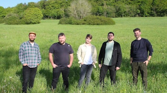 Das Bild zeigt die fünf jungen Musiker der Band „Amie & Me“ auf einer grünen Wiese.