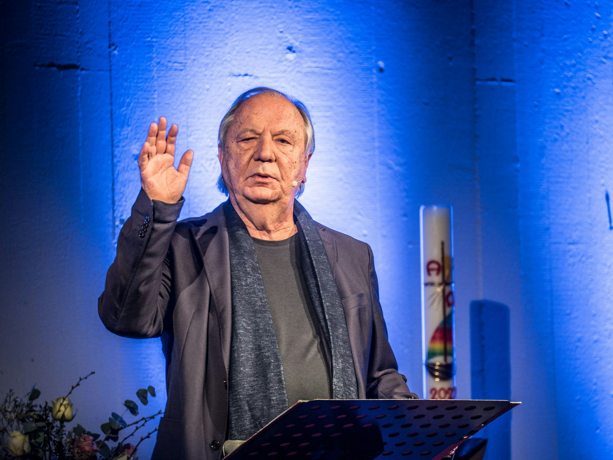 Kabarettist Wilfried Schmickler gestikuliert an einem Pult in der Friedenskirche Waldsiedlung.