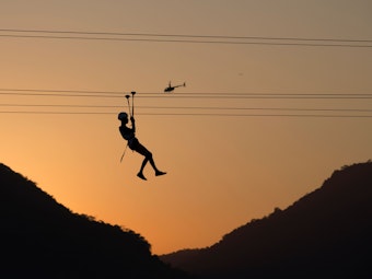 Ein Mann fährt in Rio de Janeiro (Brasilien) auf einer Seilrutsche.