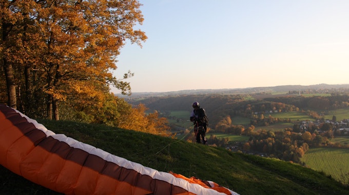 Ein Paraglider landet auf einem Hügel.