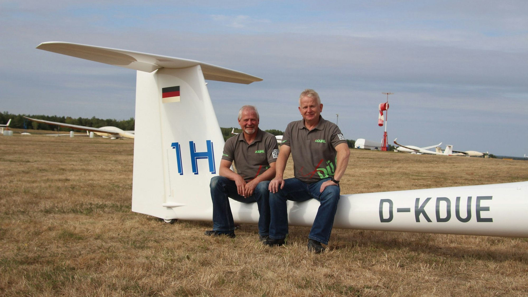 Zwei Männer sitzen auf dem hinteren Abschnitt eines Segelflugzeugs.