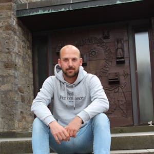 Das Bild zeigt Andreas Winkler, der auf den Stufen vor der Kirche in Marmagen sitzt.