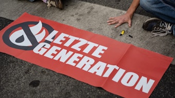 Ein Aktivist der Gruppe „Letzte Generation“, der seine Hand selbst auf der Straße festgeklebt hat, blockiert eine Kreuzung am Geismar Tor.