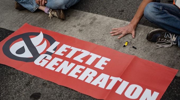 Ein Aktivist der Gruppe „Letzte Generation“, der seine Hand selbst auf der Straße festgeklebt hat, blockiert eine Kreuzung am Geismar Tor.&nbsp;