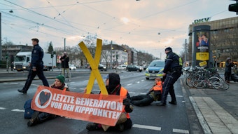 Aktivisten der „Letzten Generation“ kleben sich auf der Fahrbahn fest – Polizisten tragen Aktivisten von der Fahrbahn.